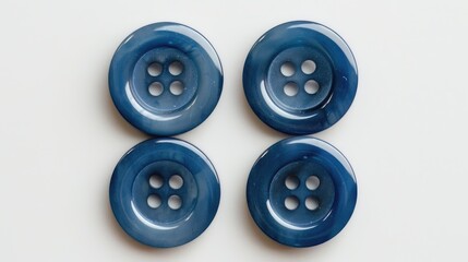 Four blue sewing buttons in a close up arrangement on a white backdrop