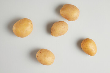 The photograph from above view on the white flat with fresh potato spread evenly above. Potato is one of the most popular ingredient in cuisine, which have a lot of nutritional value