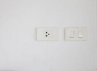 White switches and outlets mounted on a white wall leaving copy space.
