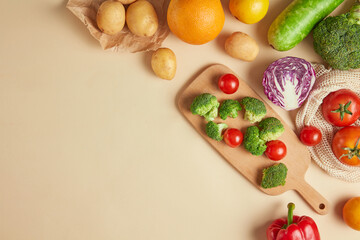 Natural fruits and vegetables concept photography, from high angle shot against yellow background. Group of vegetables and fruits spread evenly on half top corner of photo, displaying space