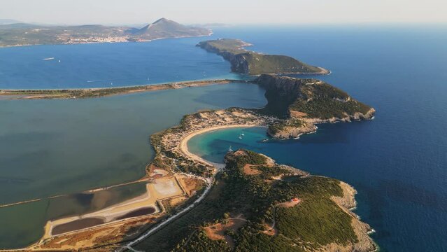 An aerial view of Voidokilia beach, a horseshoe-shaped bay in Messinia, Greece. The crystal clear waters and lush green hills create a picturesque landscape.