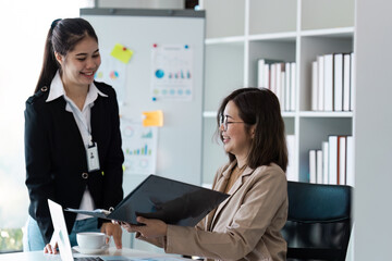 Professional Business Meeting in Modern Office Setting with Two Female Colleagues Discussing Documents and strategy