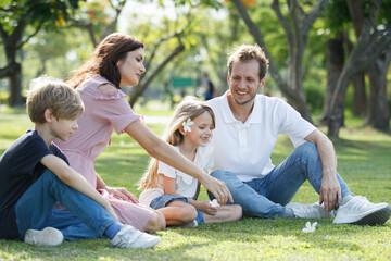 Caucasian family parent and their children picnic at the park in morning.