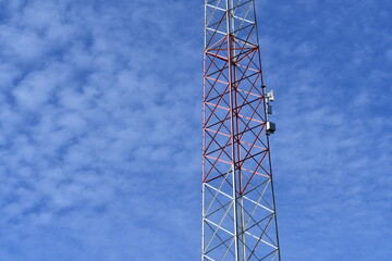 Radio tower, blue sky with small wispy clouds.