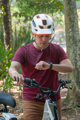 Obraz premium Latin man riding bicycle and looking at his smart watch