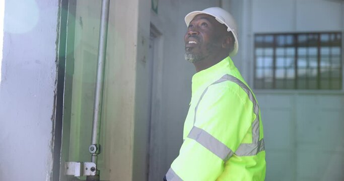 Construction worker, open and man at garage door of factory with morning routine and start of day. African engineer, professional and person with shutter roller in workshop, warehouse or working site