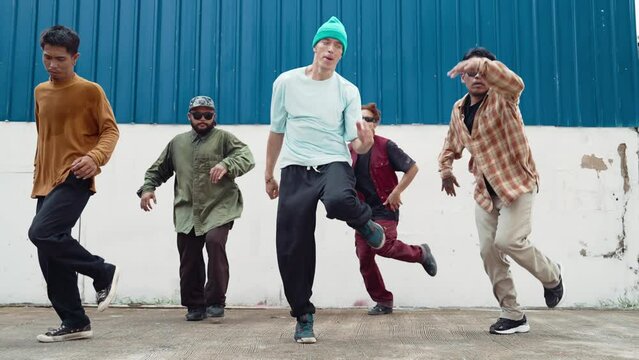 Group of hip hop choreographer dancing street dance together at wall. Young handsome dancer team practicing break dance, move to modern rhythm, express feeling of lively. Outdoor sport 2024. hiphop.