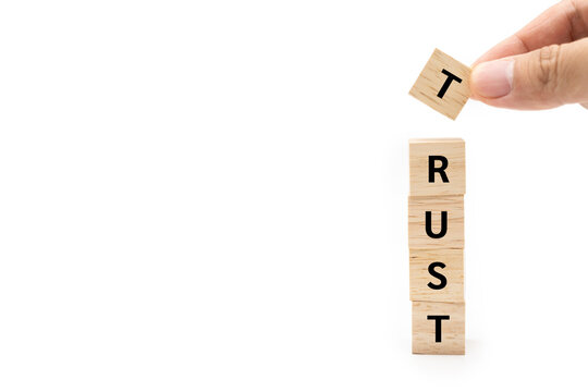 Hand putting wood cube block with TRUST text isolated on white background. Brand building for success concept. Building trust business concept.