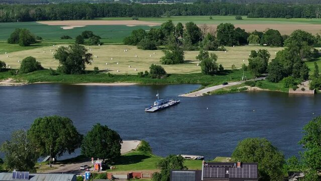 Ferry crosses the Elbe near Barby, Saxony-Anhalt. Flight from top to bottom. Buildings appear in the foreground. Landscape with trees on the other side of the river.