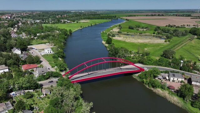 Calbe/Saale, Saxony-Anhalt. Flight from left to right. River Saale in the center. Red bridge with moving cars. Landscape with trees, meadows and fields. View towards Calbe.