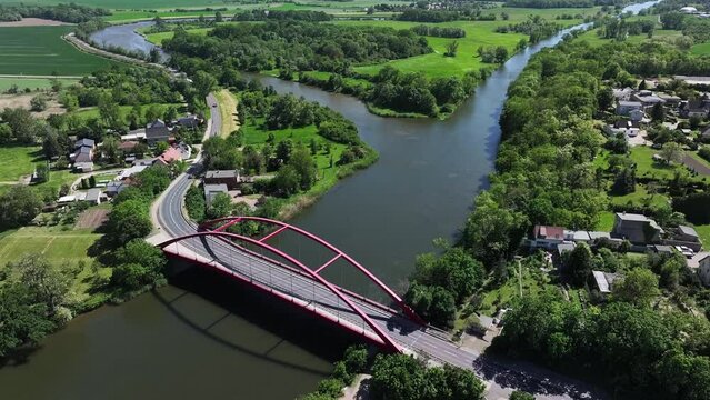 Saale Bridge Calbe in Saxony-Anhalt. Movement with camera panning. Aerial view from the red bridge over the Saale towards Nienburg. Outskirts of Calbe. Saale cycle path over the bridge.