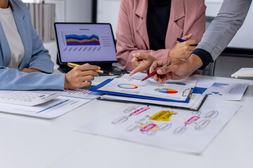 Group of confident business people point to graphs and charts to analyze market data, balance sheet, account, net profit to plan new sales strategies to increase production capacity. 