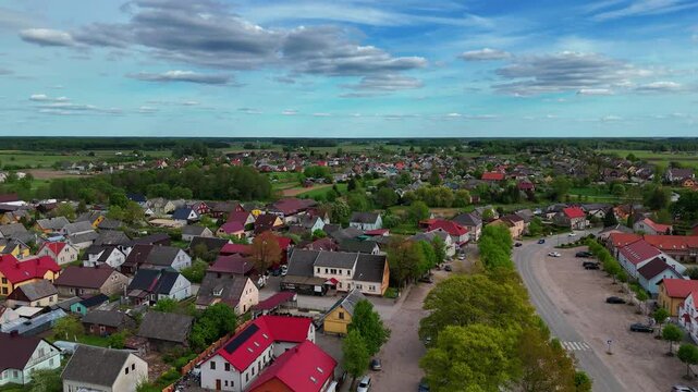 Drone shot of a small village in Lithuania surrounded by green fields under the clear sky, Sveksna