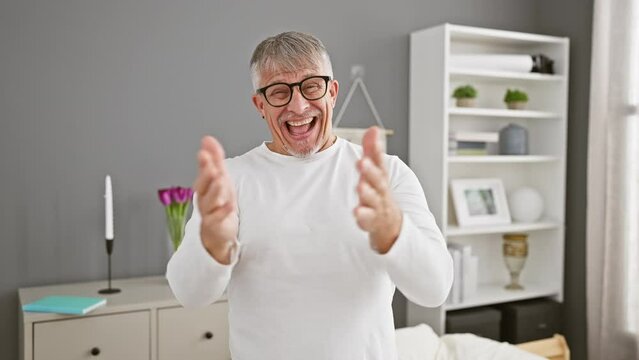 Cheerful middle age grey-haired man in pyjamas offering a helping hand with warmth and acceptance from his cosy bedroom.