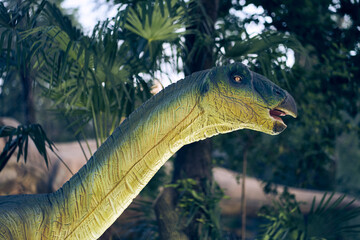 Dinosaur head close-up in the park. Giant Therizinosaurus on display in the park on a summer day in...