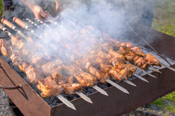 BBQ close up. A person is cooking meat on a grill, and the smoke is rising