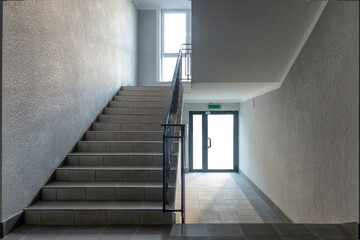 Staircase in the entrance of a modern house. There are walls, steps, a window and an entrance glass door. Background.