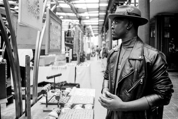 Monochrome image of man looking at jewelry in a street market stand.