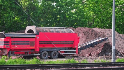 Industrial Drum Screening Machine Operating on Construction Site Sieving Soil and Separating Rocks...