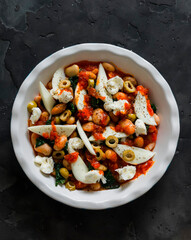 Cooking delicious snack, appetizer, tapas - baked beans with spinach and mozzarella on a dark background, top view
