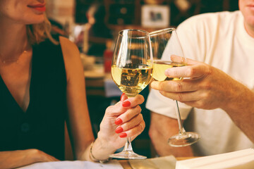 closeup with cropped shot of lovers holding hands over romantic valentine’s day dinner table.Couple clinking glasses at Christmas day in restaurant.Happy young couple enjoying nice romantic dinner.