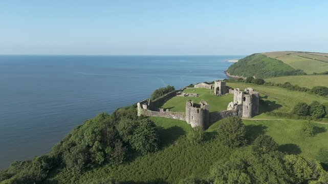 An aerial view of the of Llansteffan Castle in Carmarthenshire, South Wales, on a sunny morning with a clear blue sky. Circling left to right around the Castle.