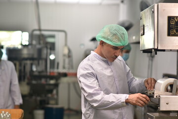 Worker in food factory chceking machine for packing product.