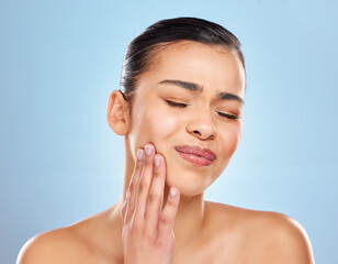 Toothache, pain and woman in studio with dental problem for cavity crisis and decay from bacteria. Female person, hand on face and jaw injury with surgery for teeth extraction by blue background