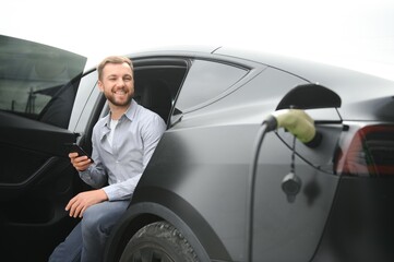 Man charging electric car by the house