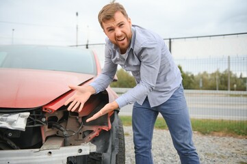 A frustrated man near a broken car. Grabbed my head realizing the damage is serious, the car is...