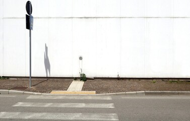 Weathered white concrete wall with air intake. Sidewalk, pedestrian crossing sign, crosswalk and...