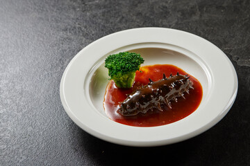 traditional chinese wok fried seafood fresh sea cucumber with dark oyster soy thick abalone sauce in plate on grey stone table asian cafe hotel luxury halal food restaurant banquet menu