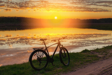 Obraz premium Bicycle on the shore of a lake in summer at sunset.