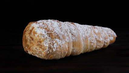 Tube cake with white cream on a dark background. Puff pastry pastry.