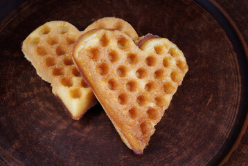 Венские вафли в форме сердца оставляют на глиняной тарелке.