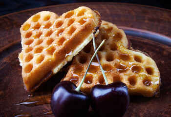 Heart-shaped Viennese waffles drizzled with honey lie on a clay plate. Viennese waffles with...
