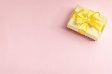 Invitation or greeting card mockup with yellow gift box on pink background. Copy space.