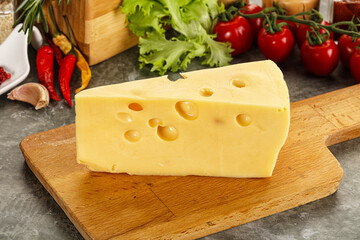 Swiss Maasdam cheese triangle over board