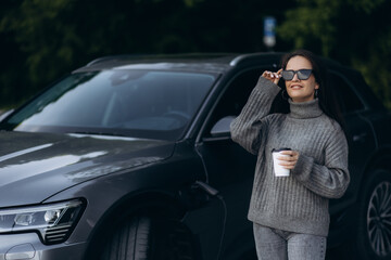 Woman charging electro car at the electric gas station