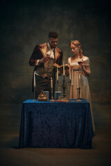 Cozy evening atmosphere. Elegant young woman and handsome man, royal family standing by the table...