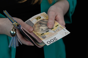 Kobieta trzyma w dłoniach portfel i płaci gotówką, polskie banknoty pln