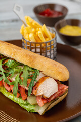 Grilled chicken breast sandwich with french fries and sauces