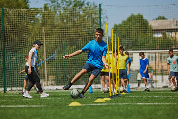 Teamwork and Agility. Young soccer players in uniforms raining outdoors on football field with...