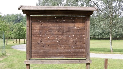 Noticeboard advertising sign with wooden structure with public park background in summer.
