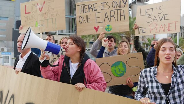 Group of diverse people holding placards and posters on global strike with megaphone leading climate change protest