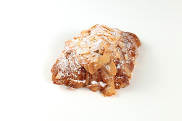 Almond croissant. puff pastry, delicate frangipane cream with almonds, enriched with butter. On top, the croissant has a hint of almond flakes and powdered sugar. on a white background