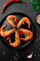 Large cooked king prawns on a black background. Lemon slices