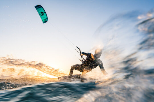 Kitesurfer surfing in sunset conditions with blue water and motion blur at the baltic sea