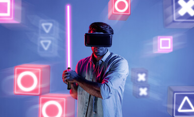 Energetic man with VR glasses fencing neon sword with music block. Professional gamer playing a...