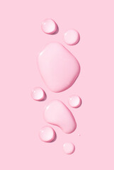 round drops of transparent gel serum on pink background